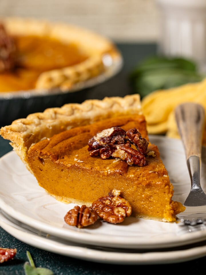 Sliced pie on stacked white plates with a fork and the whole pie in the background.