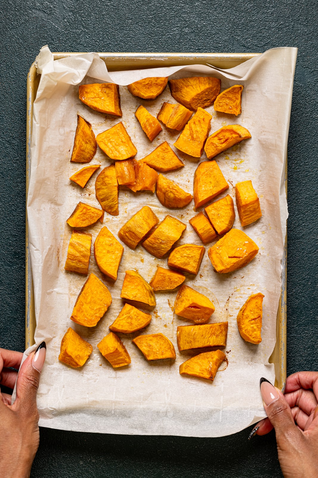 Roasted sweet potatoes on a baking sheet with parchment paper.