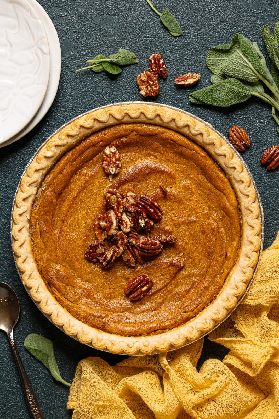 Sweet potato pie with pecans and white plates.