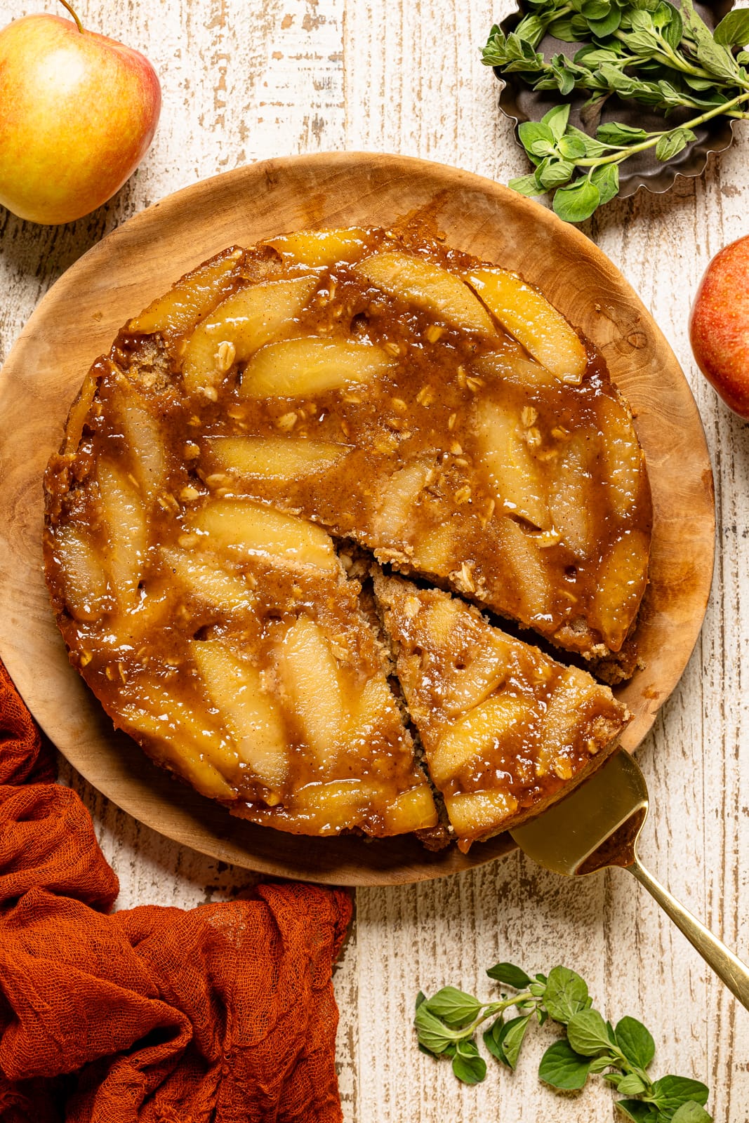 Upside down cake on a wood platter with apples.