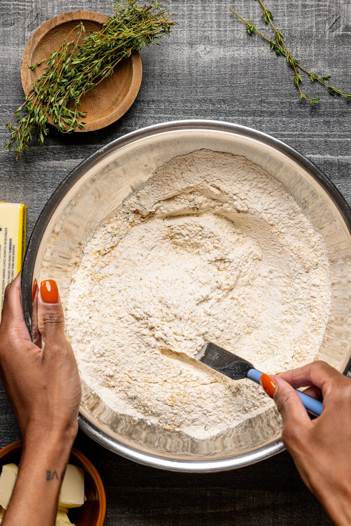 Dry ingredients in a silver bowl being stirred with a knife.