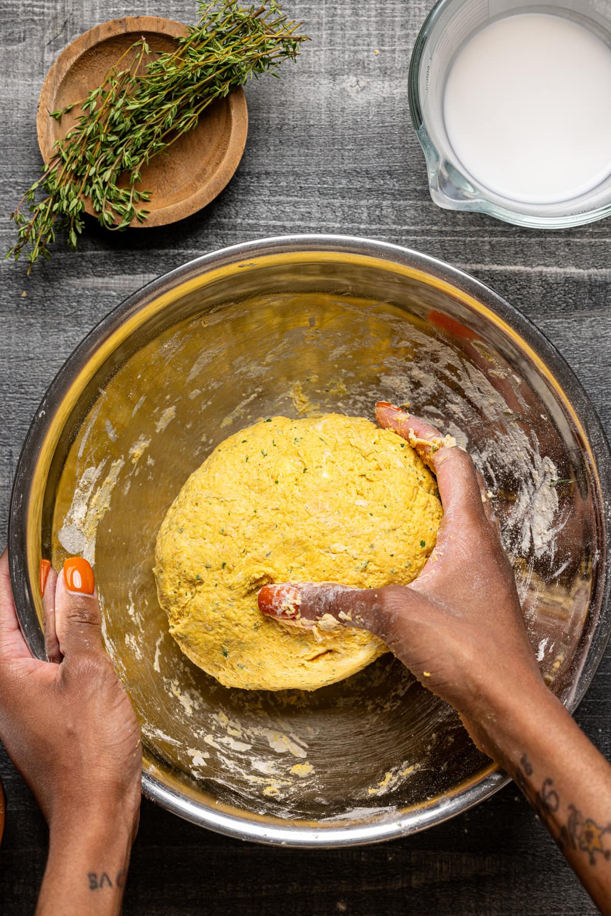 Patty dough ball in a silver bowl being kneaded. 