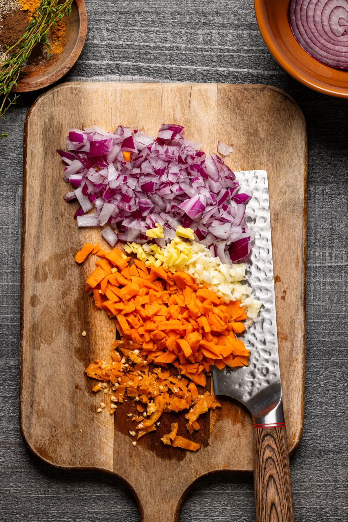 Chopped veggies on a cutting board with a knife. 