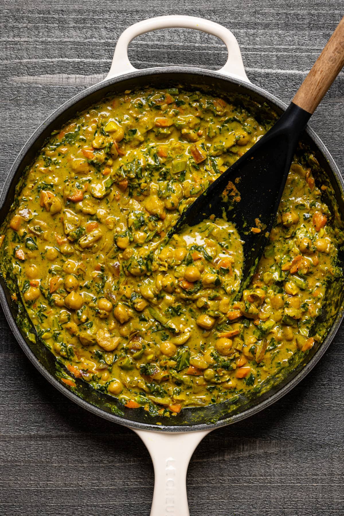 Curry filling in a skillet with a black spoon.