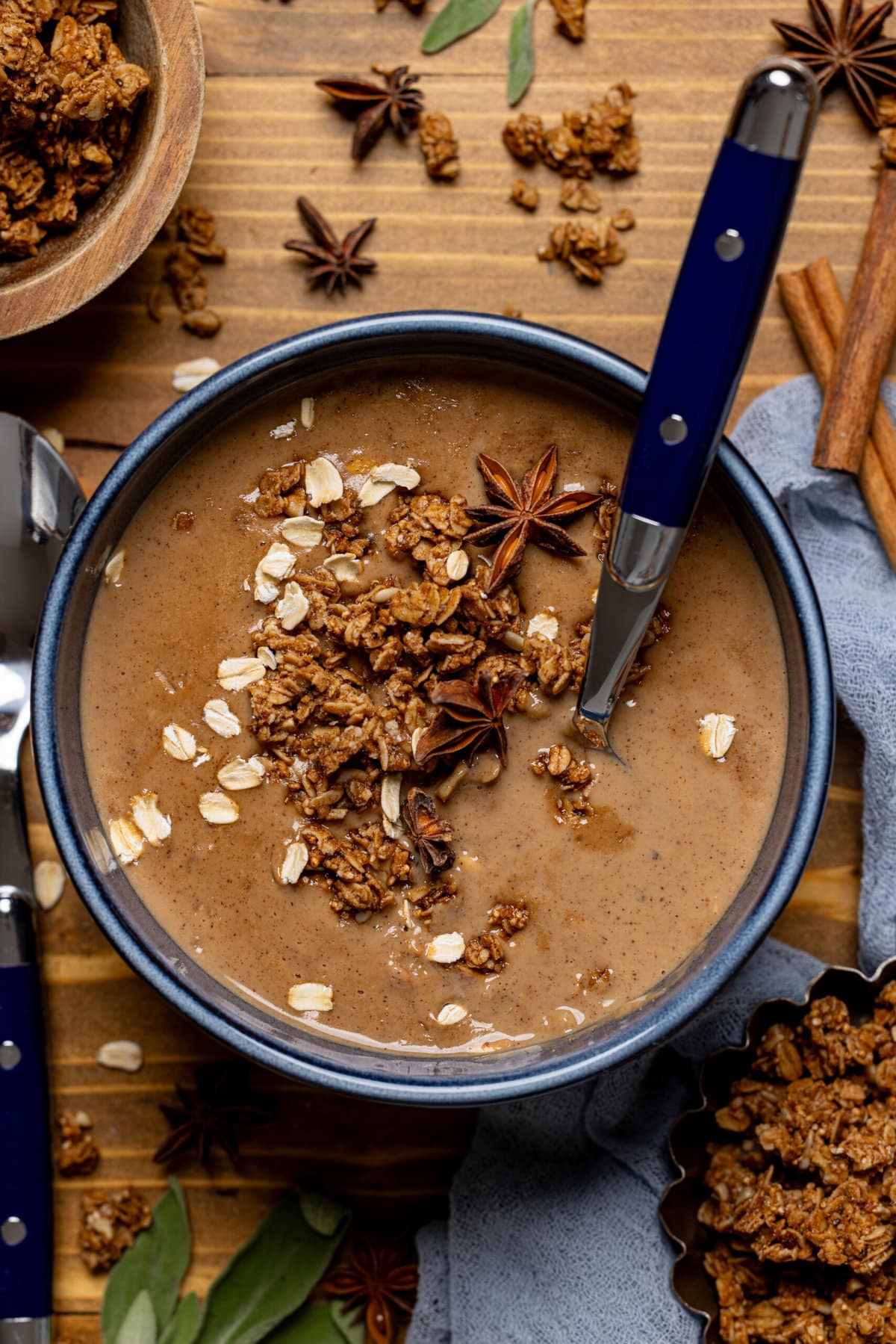 Dirty chai latte oatmeal porridge in a blue bowl with two spoons on a brown wood table.