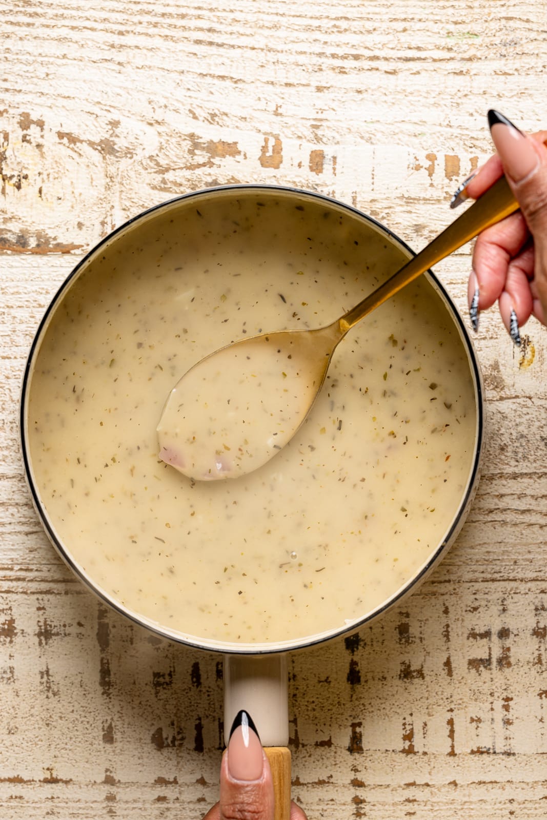 Pot with gravy being held with a spoon.