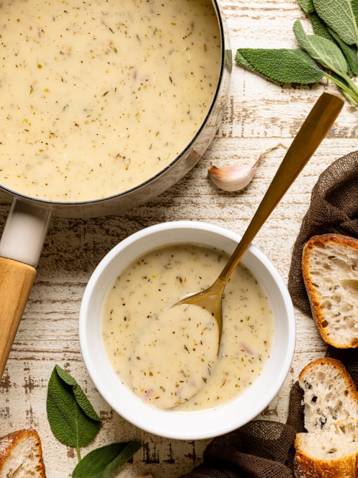 Gravy in a pot and bowl with a spoon and side of bread.
