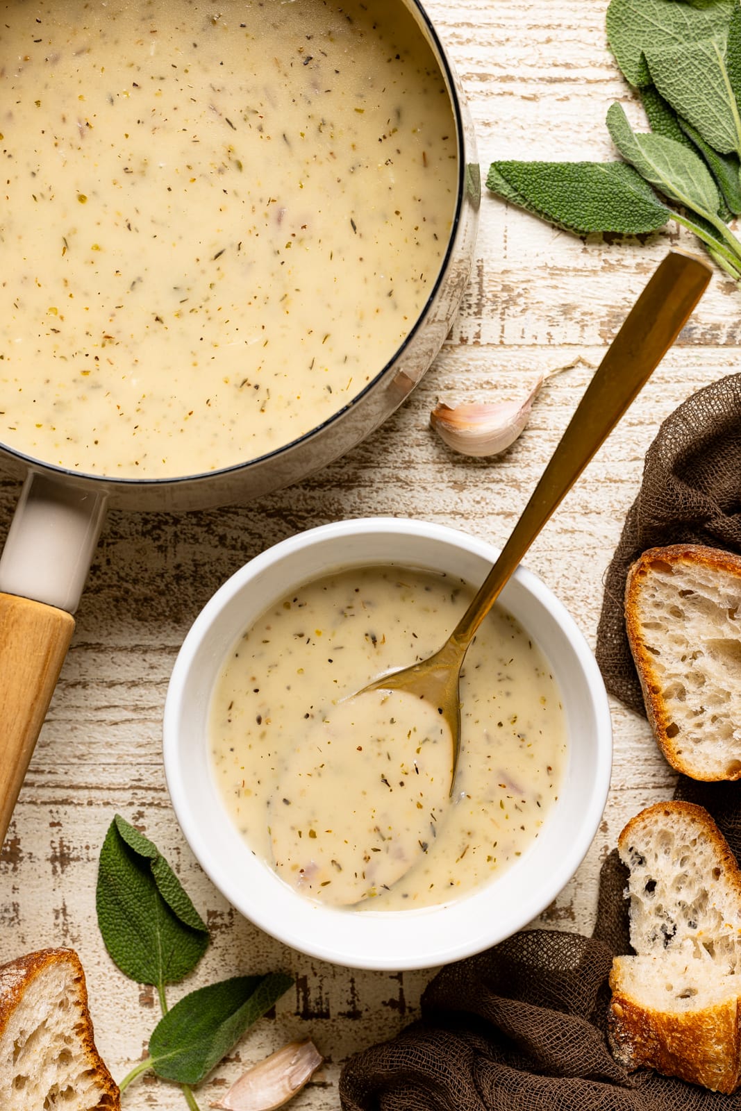 Gravy in a pot and bowl with a spoon and side of bread.