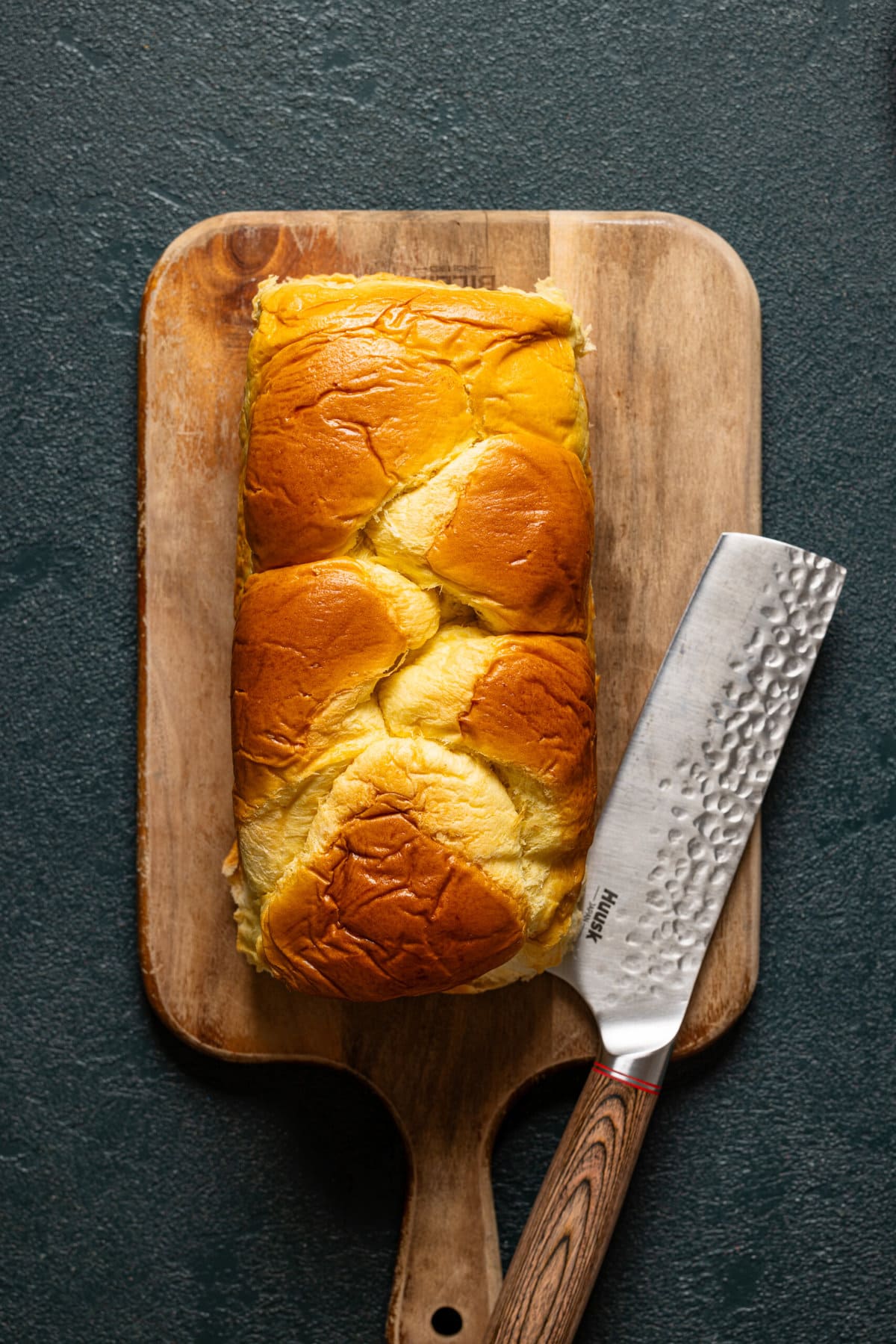 Loaf of bread on a cutting board with a knife.