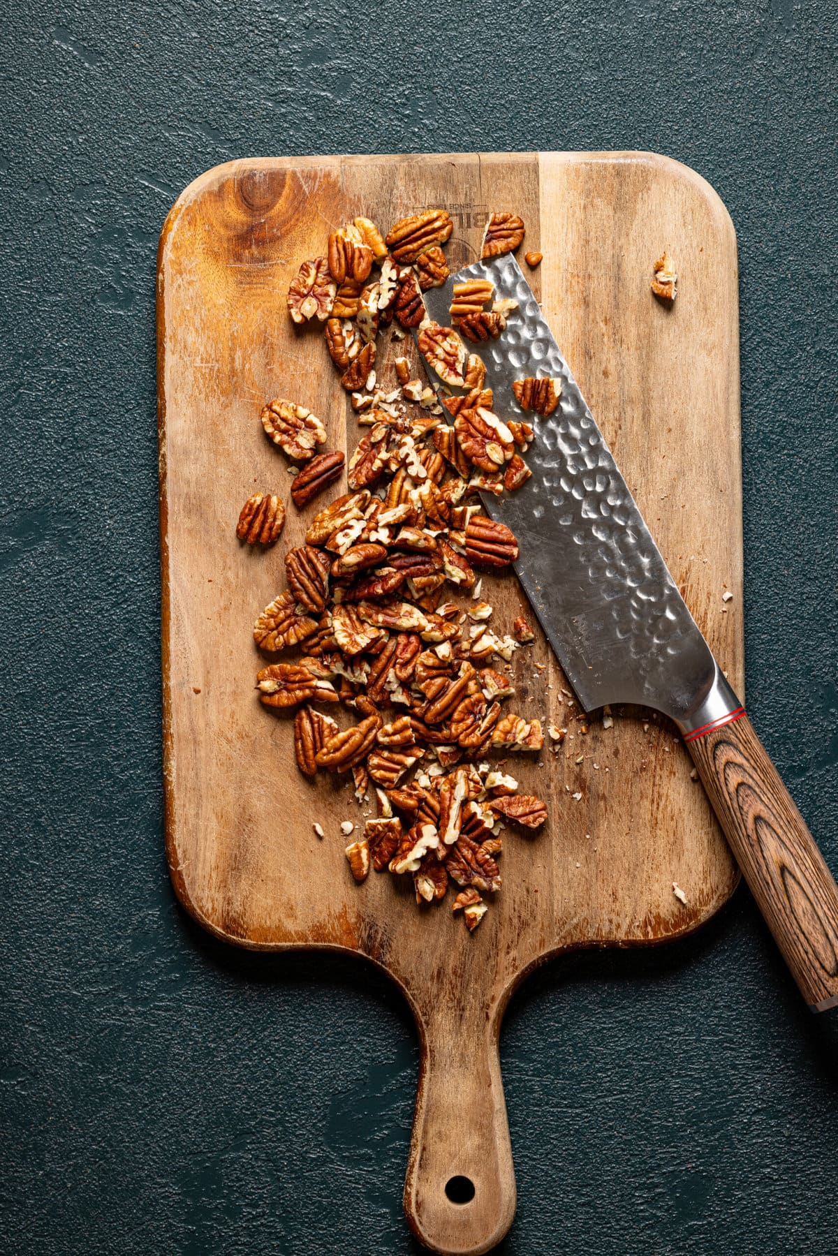 Chopped pecans on a cutting board with a knife.