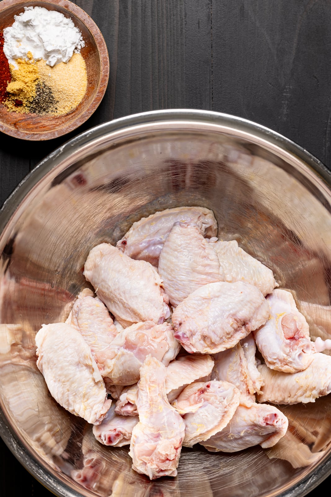 Chicken wings freshly washed in a silver bowl with seasoning.