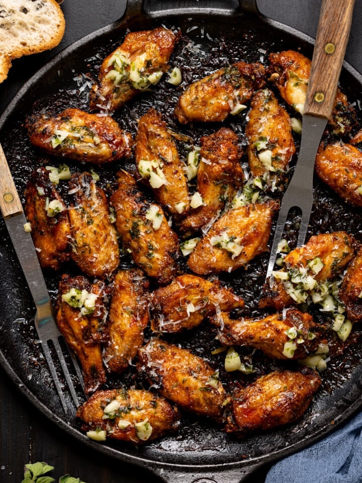 Baked chicken wings on a skillet with two forks.