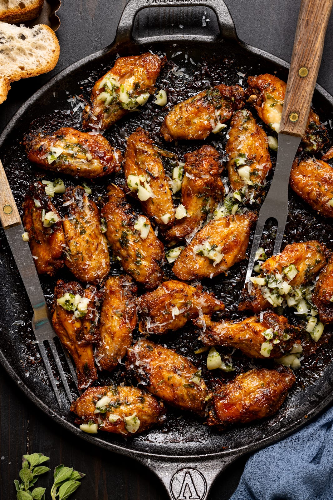 Baked chicken wings on a skillet with two forks.