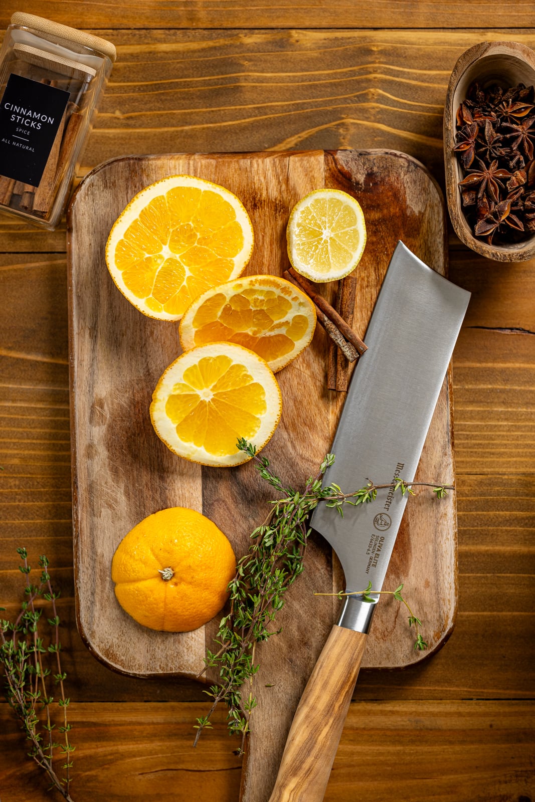 Sliced oranges and lemon with ingredients on a cutting board with knife.