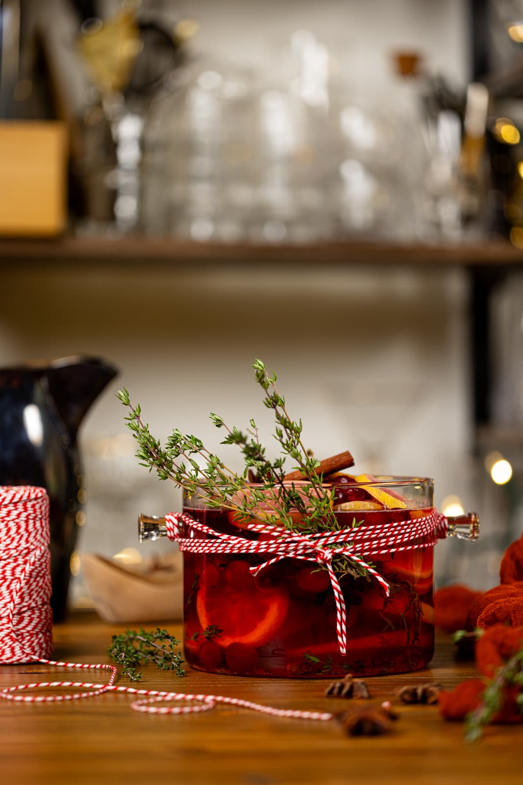 Holiday simmer pot with red string and garnish on a brown wood table.