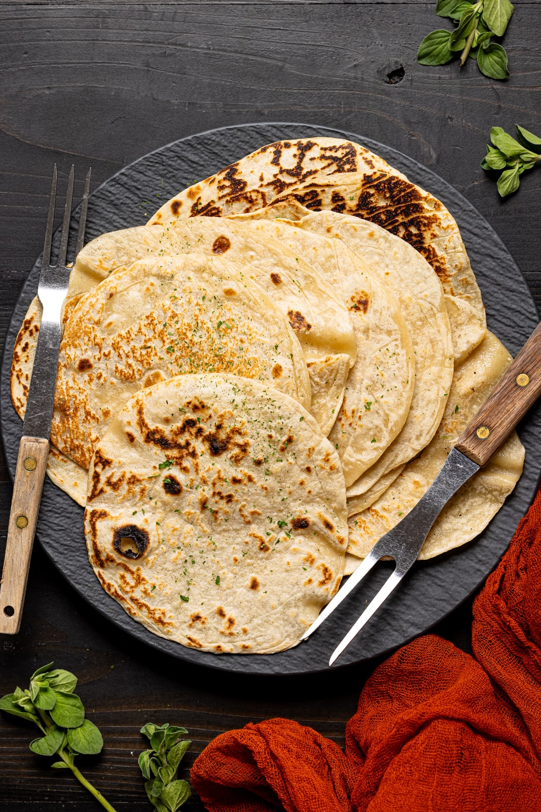Tortillas on a black plate with two forks.