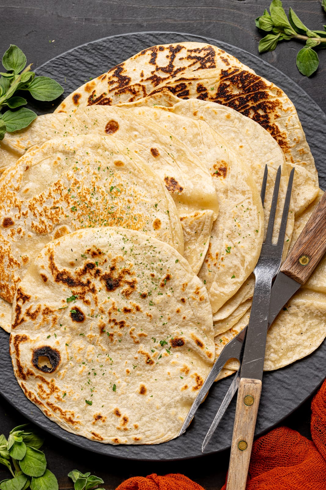 Up close shot of tortillas on a black plate with two forks.