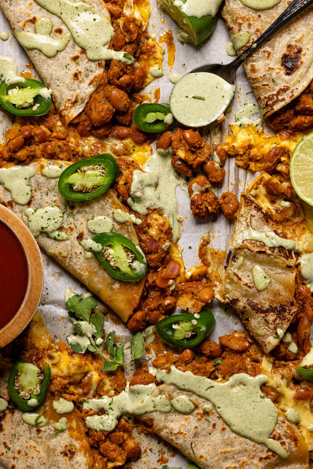 Tacos on a baking sheet with a variety of toppings and sauce.