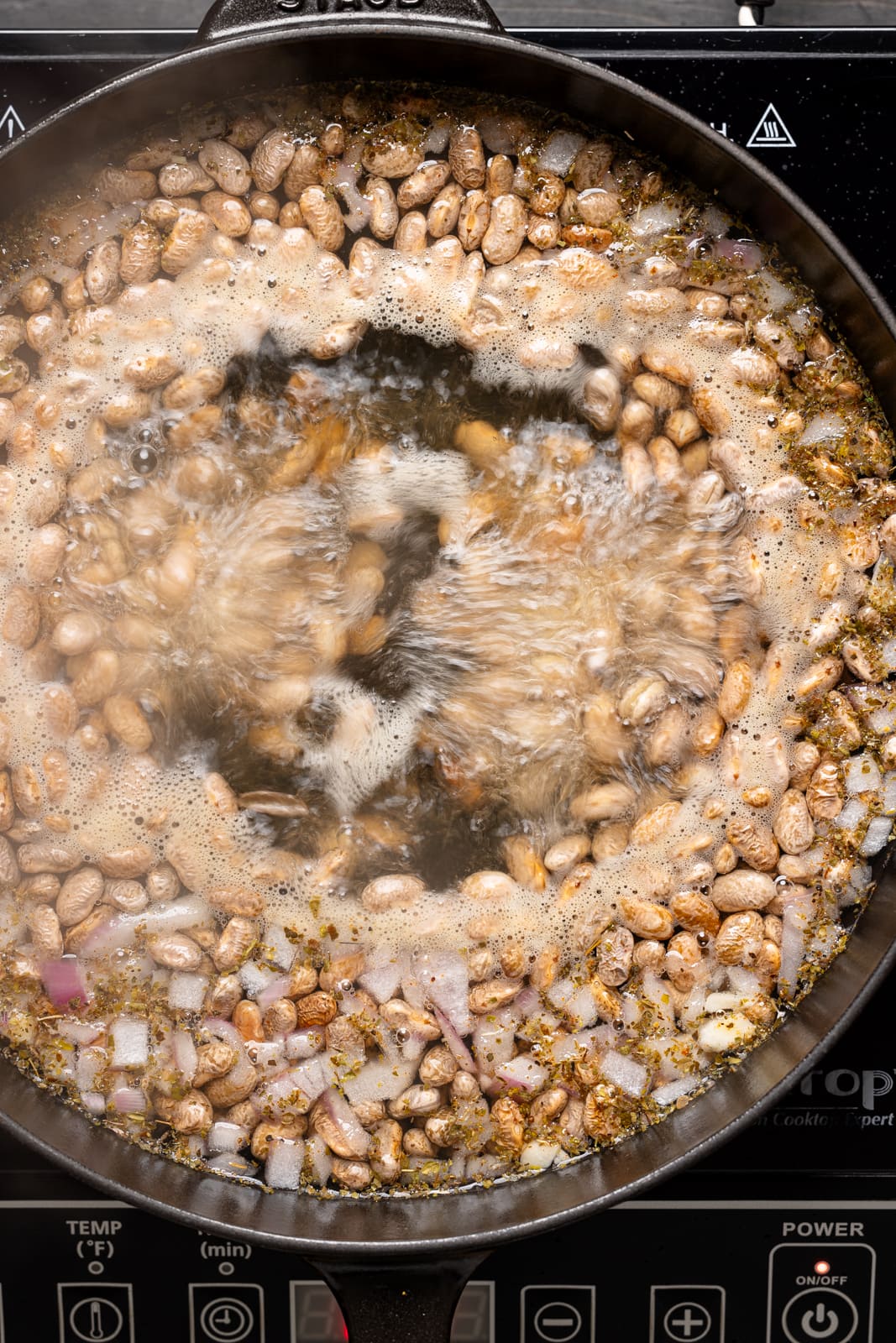 Pinto beans being boiled in a pot.