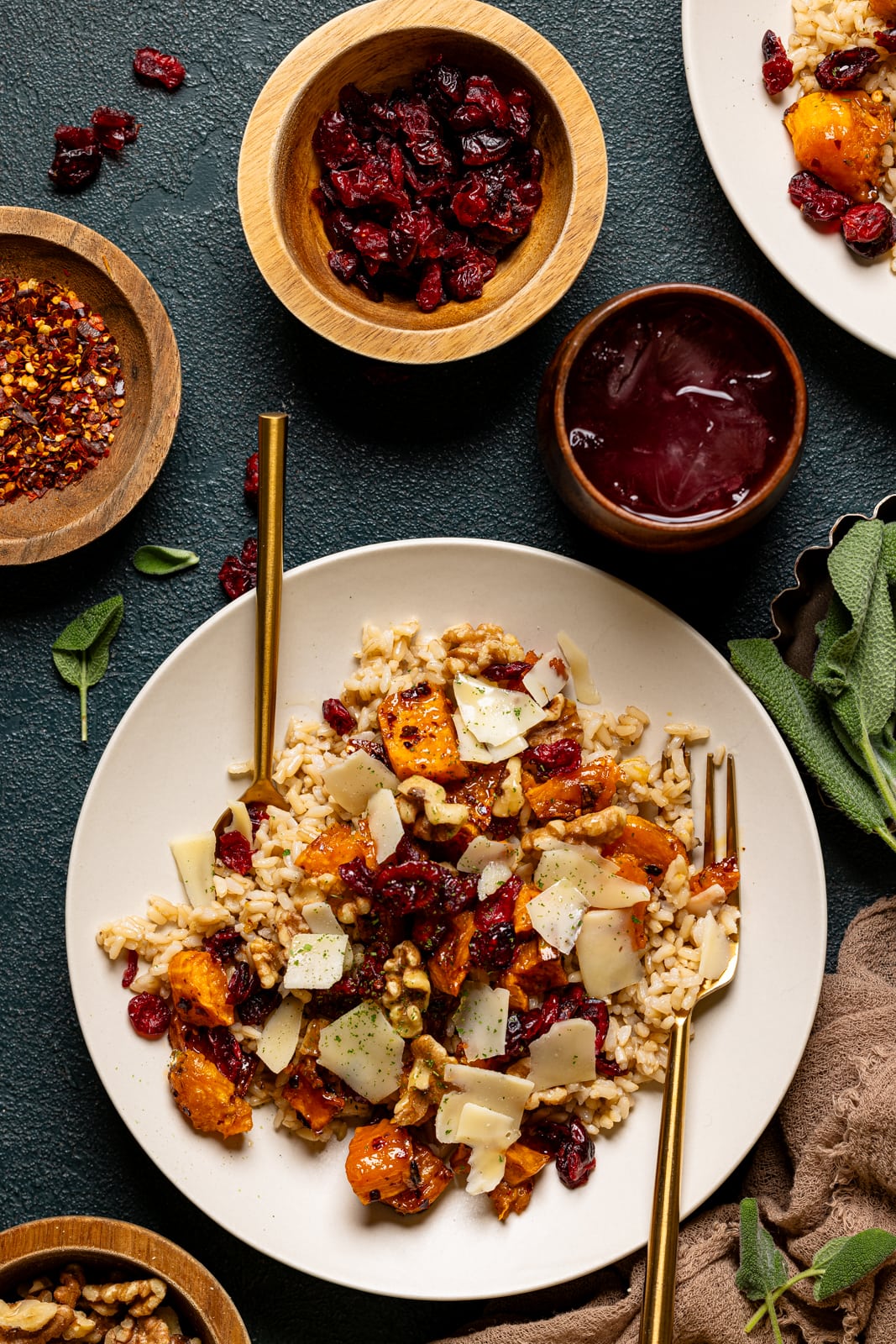 Two potato bowl on a white low bowl with two forks, drink, and bowls of garnish. 