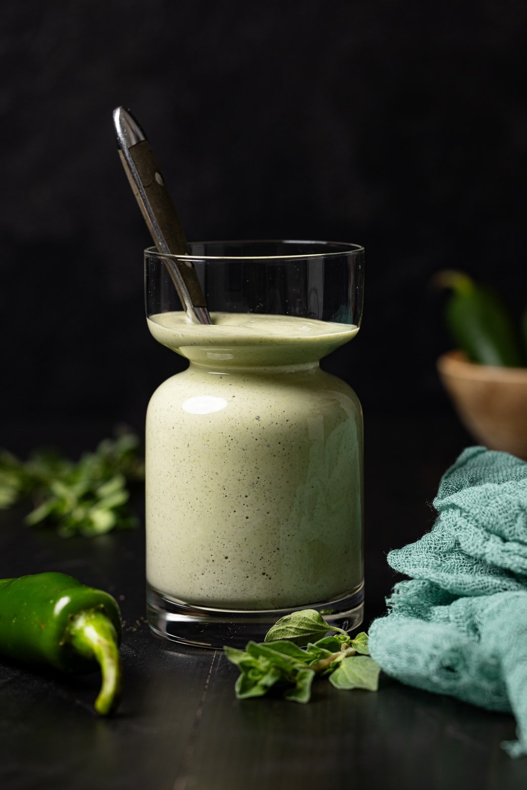 Sauce in a jar with a spoon and jalapenos.