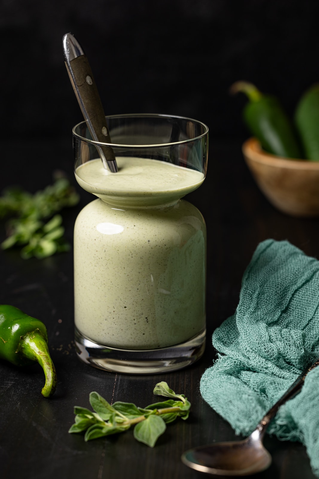 Sauce in a jar with a spoon and jalapenos.