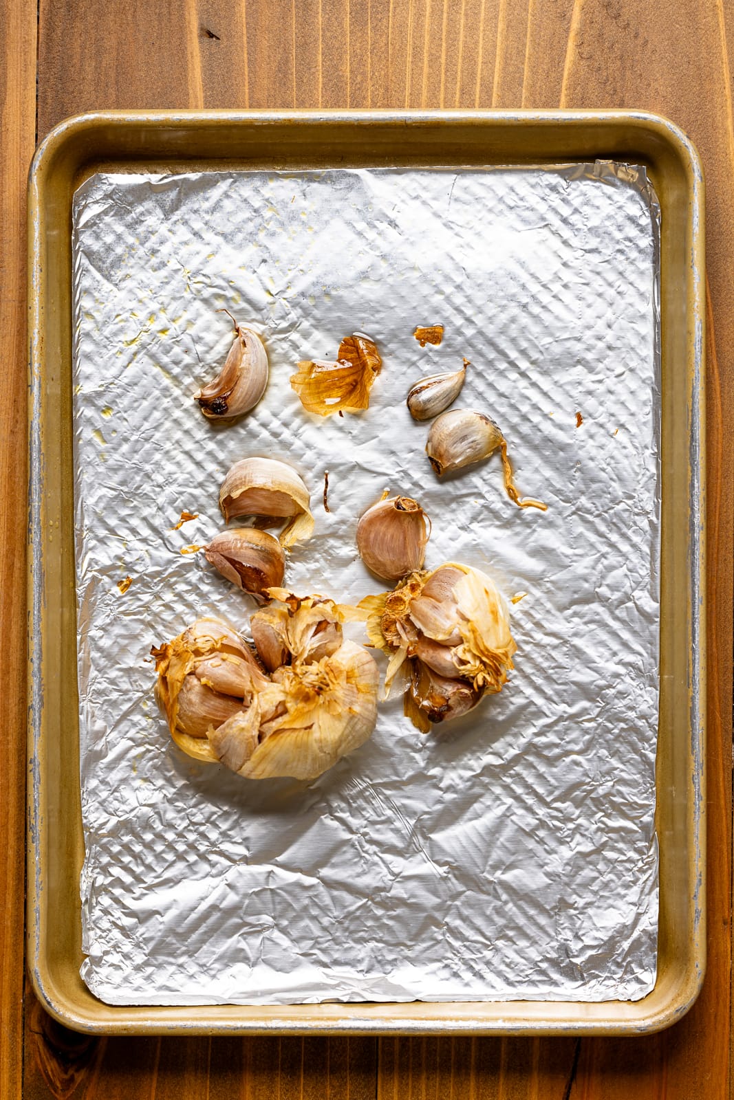 Roasted garlic bulbs on a baking sheer with foil.
