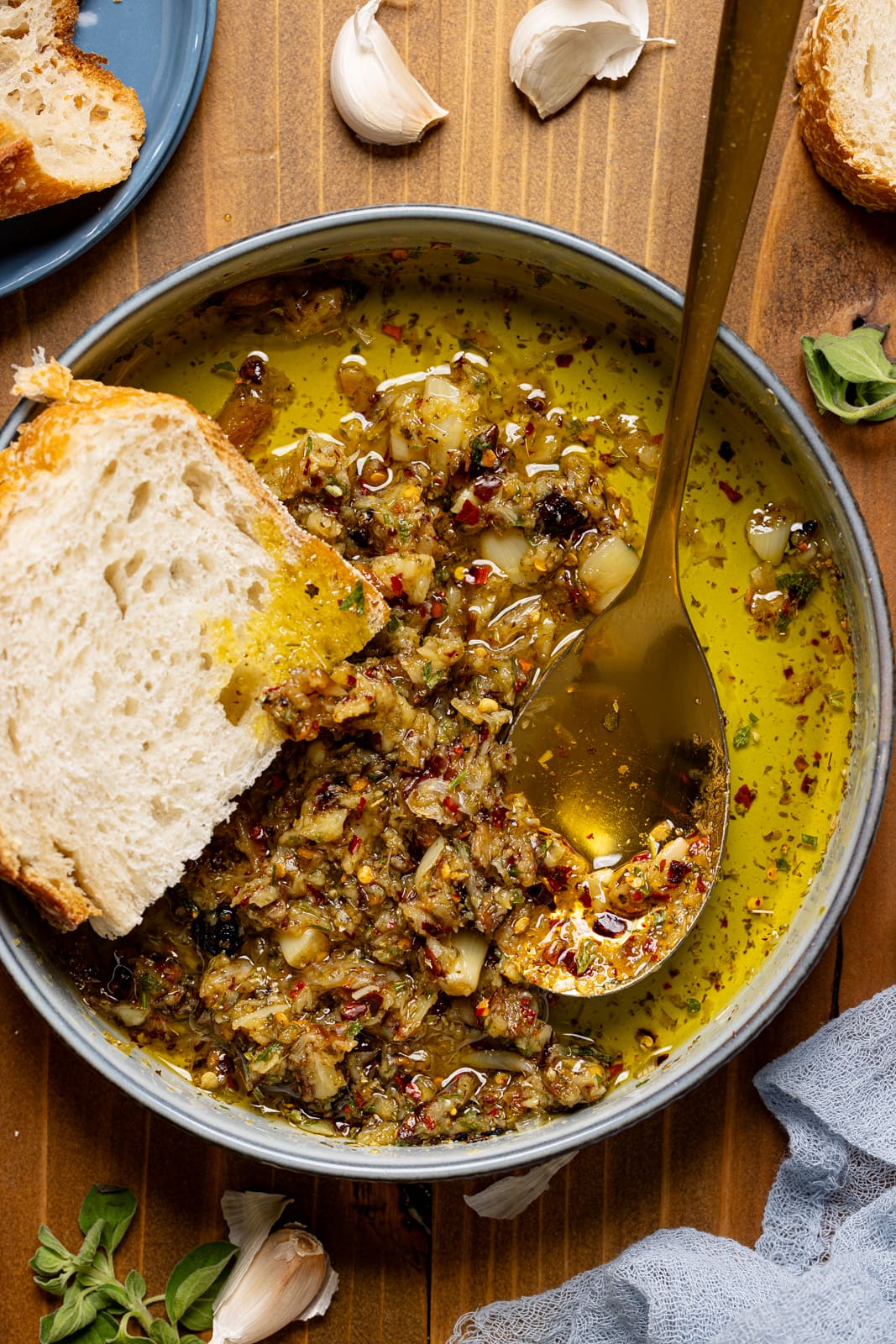 Up close shot of garlic dip in a bowl with a spoon and piece of bread.