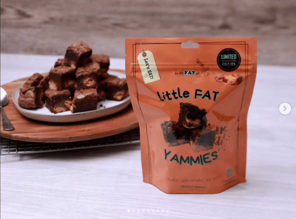 Image of a bag of brownies in an orange bag with a plate of brownies in the background. 