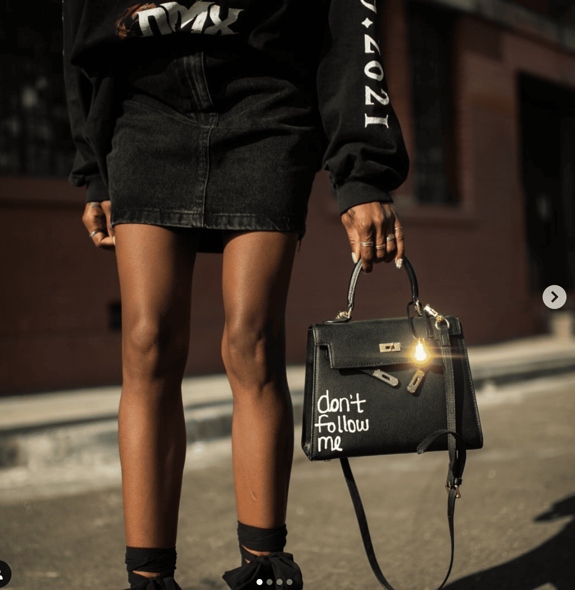 Image of person in all black holding a black handbag. 