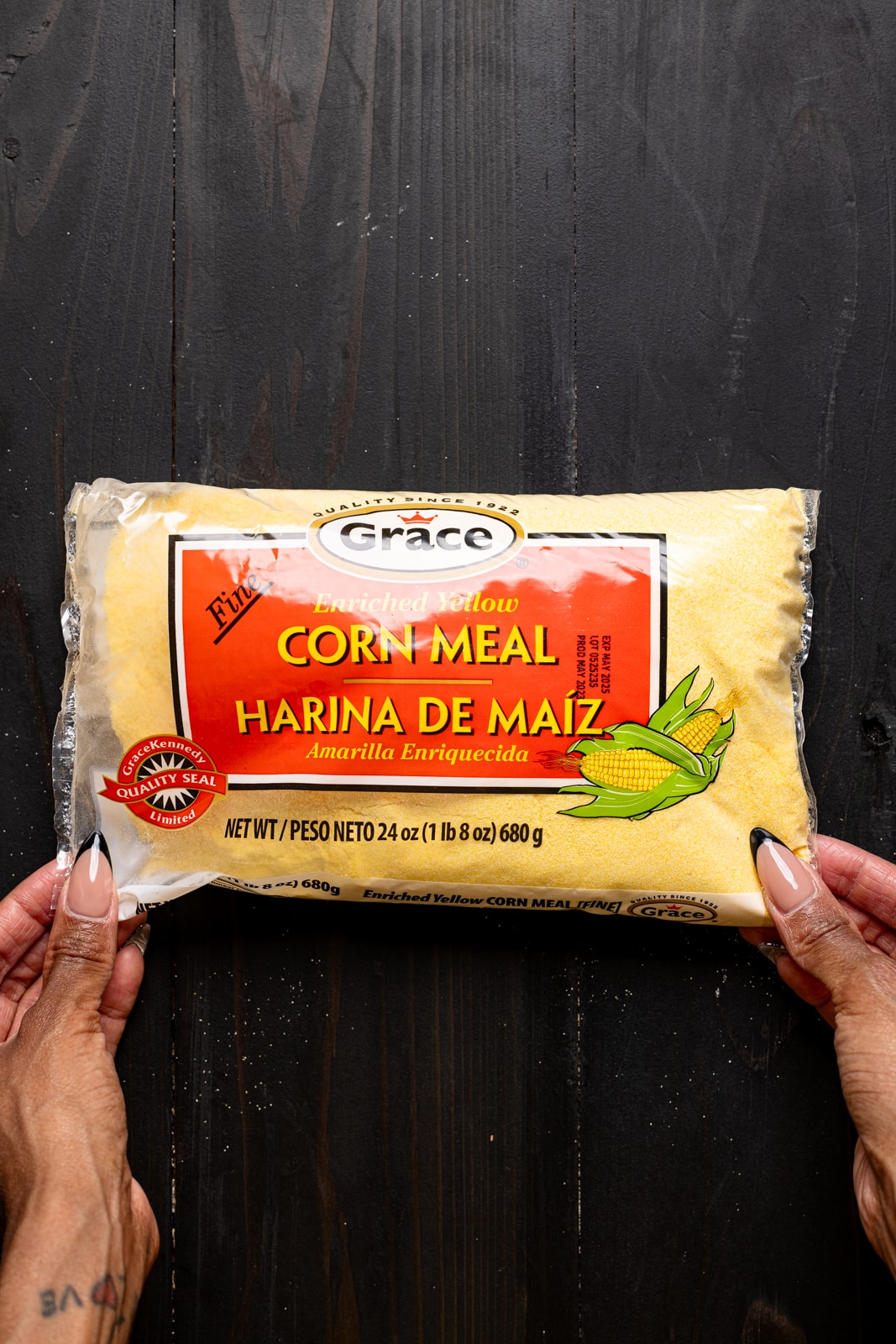 Bag of cornmeal being held on a black wood table.