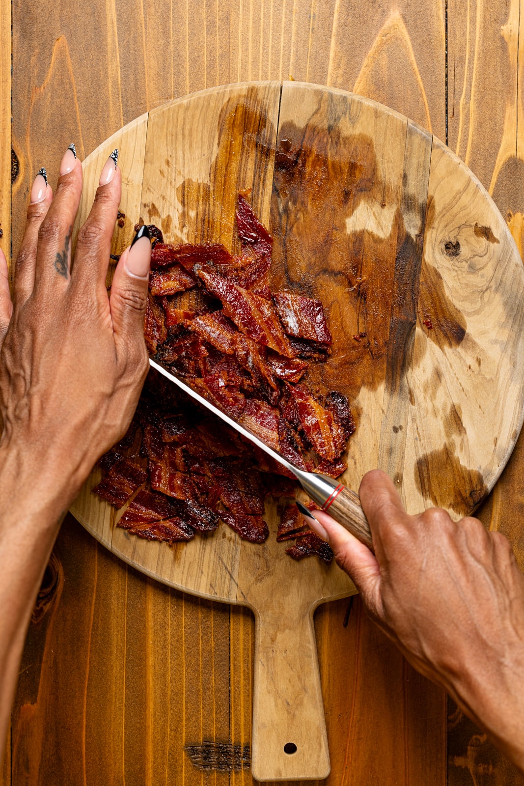 Chopping of bacon on a cutting board using a knife.