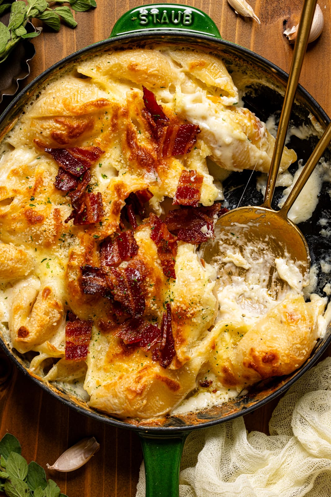 Baked mac and cheese in a green skillet with two spoons.