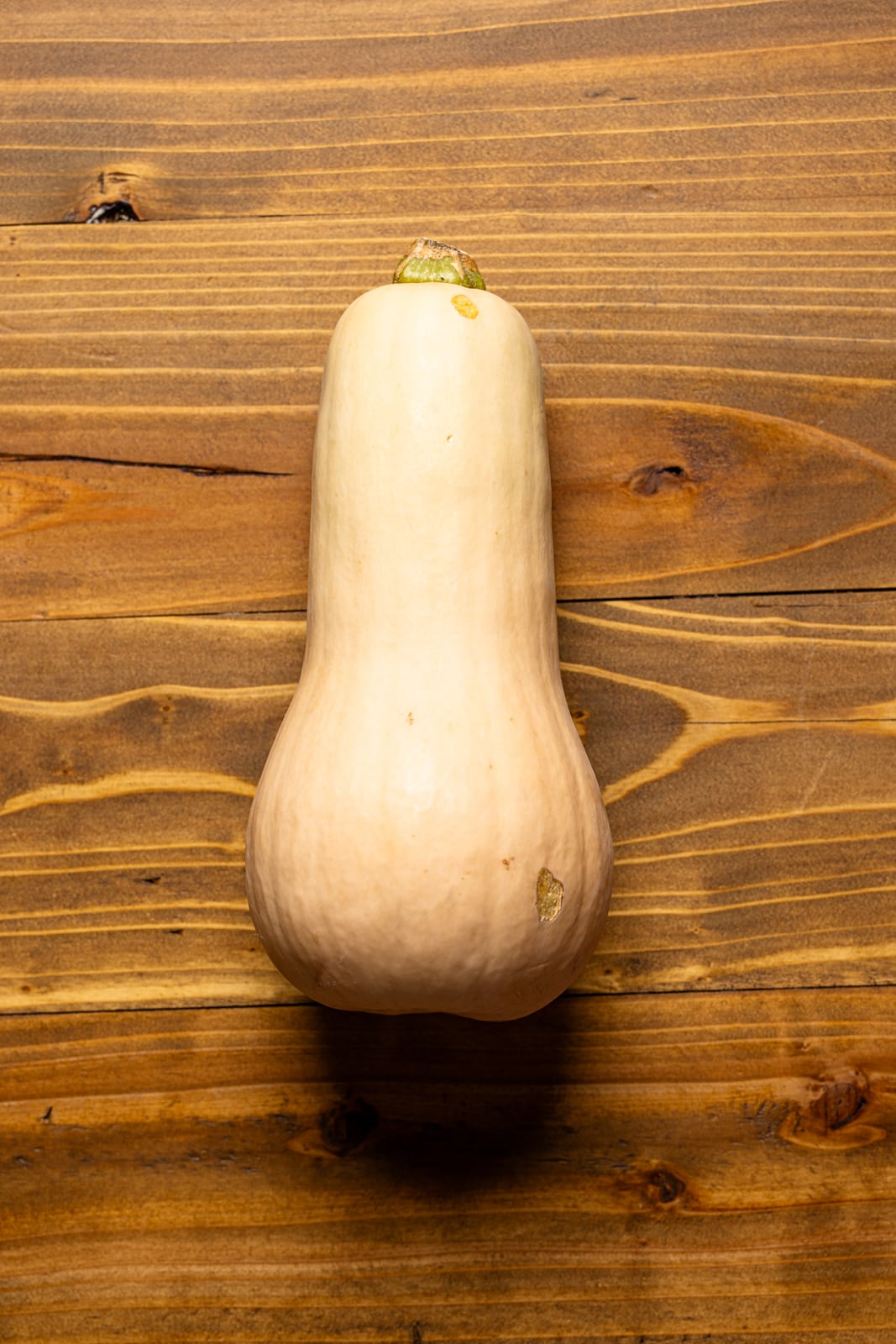 Butternut squash on a brown wood table.