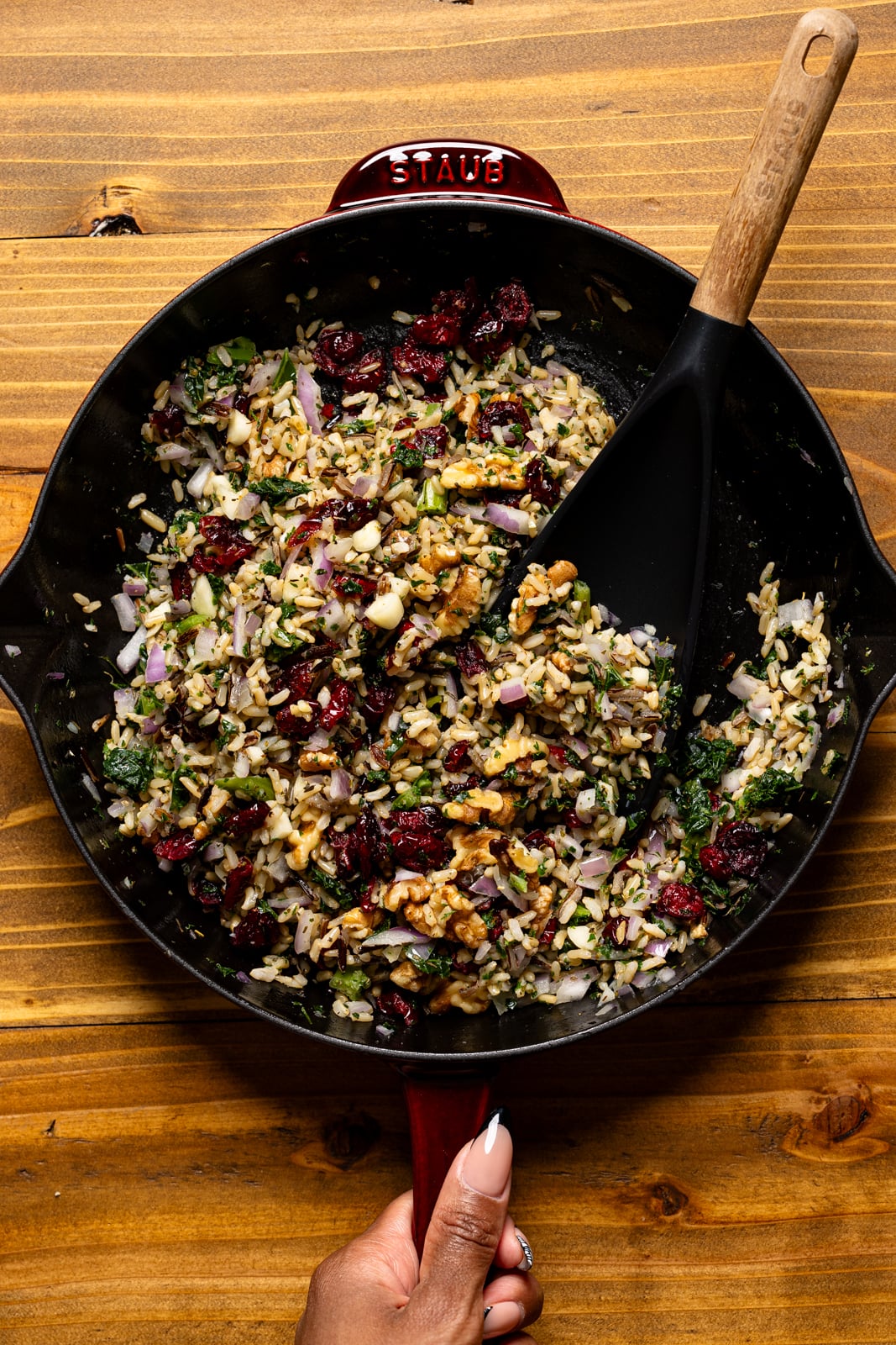 Rice filling in a burgundy skillet with a black spoon.