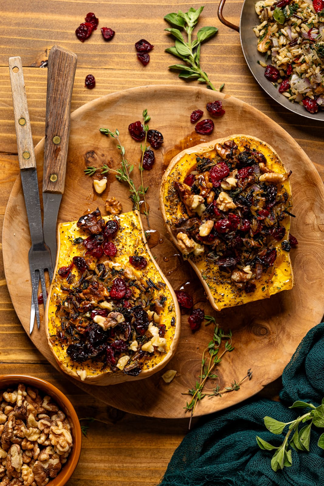 Stuffed butternut squash on a brown wood plate with two forks and garnish. 