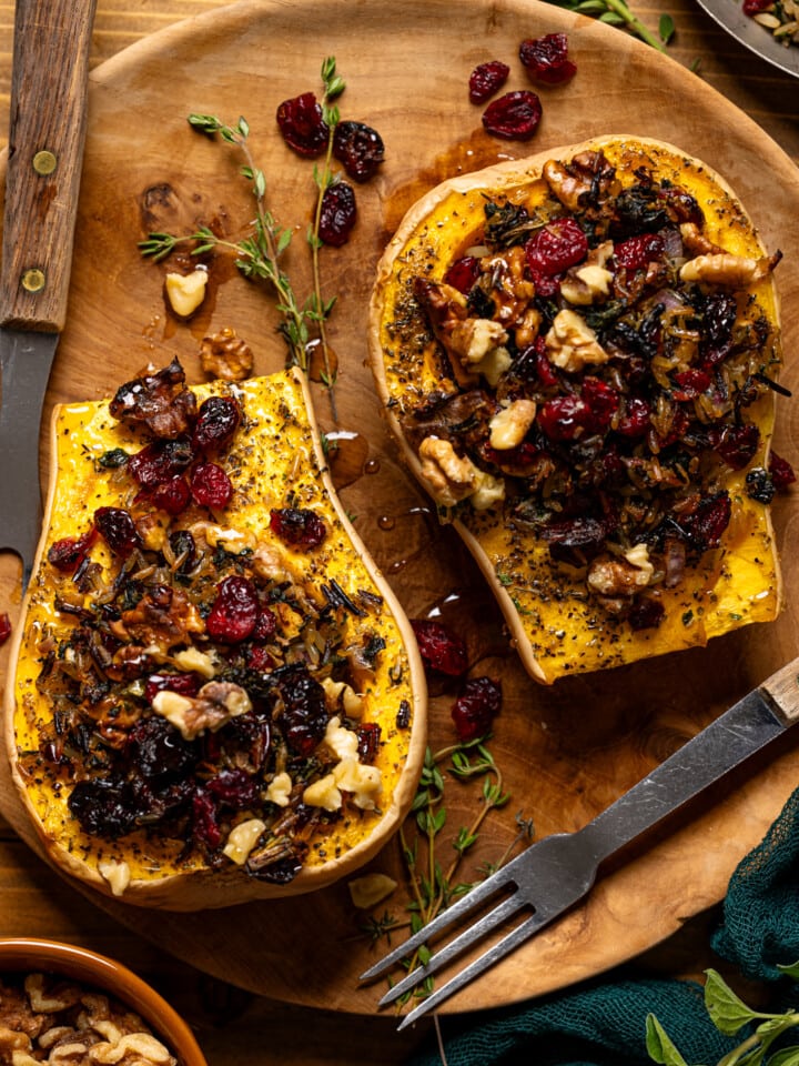 Up close shot of stuffed butternut squash with two forks and garnish.