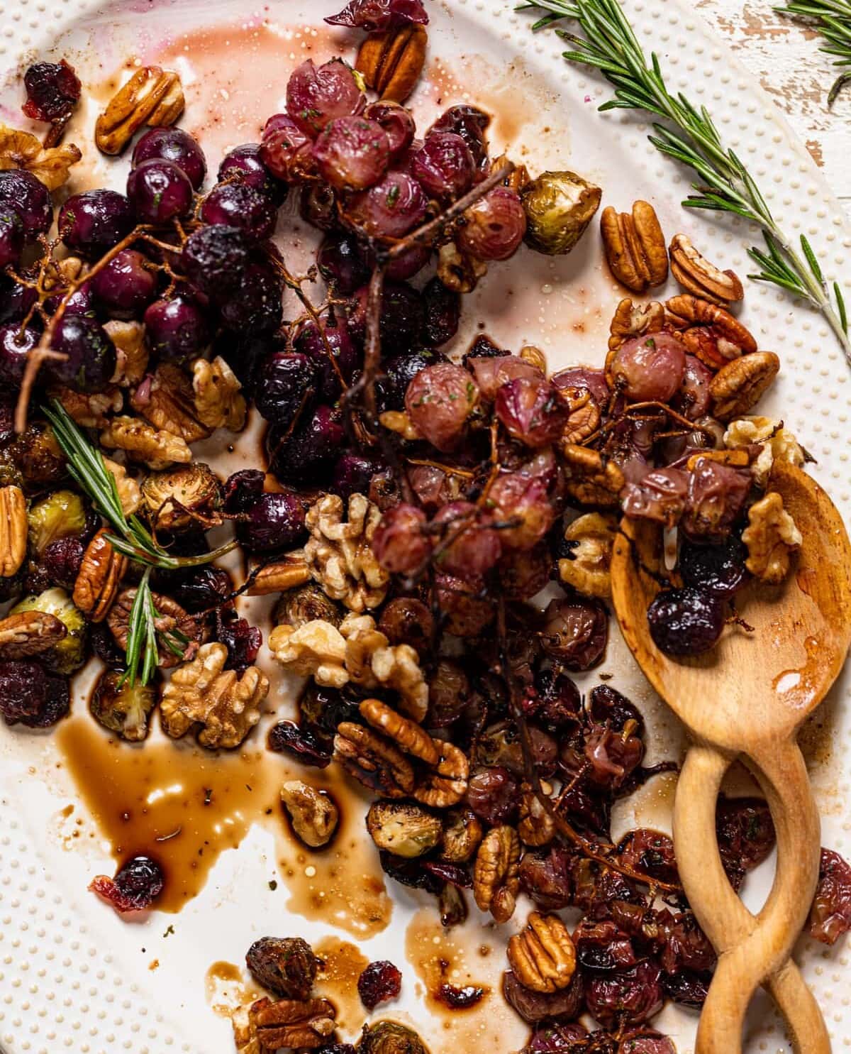 Wooden spoon on a half-served platter of Roasted Grapes and Brussels Sprouts