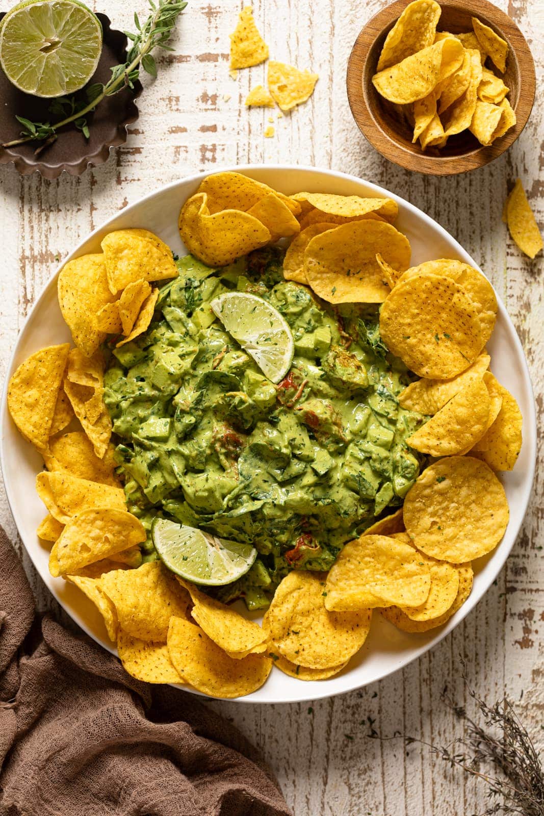 Overhead shot of Green Goddess Salad Dip surrounded by chips and topped with lime wedges