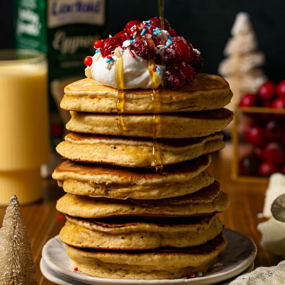 Pancakes with syrup and eggnog in background.