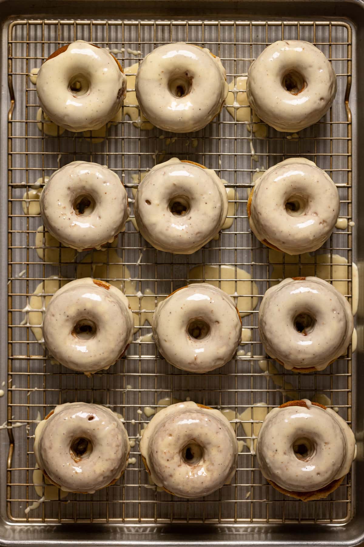 Overview of donuts atop a cooling rack with glaze.