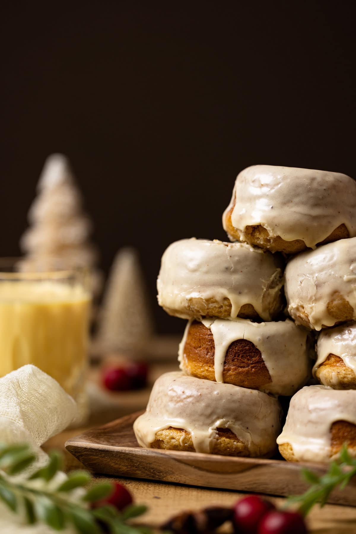 Stack of eggnog donuts with a glass of eggnog on the side.
