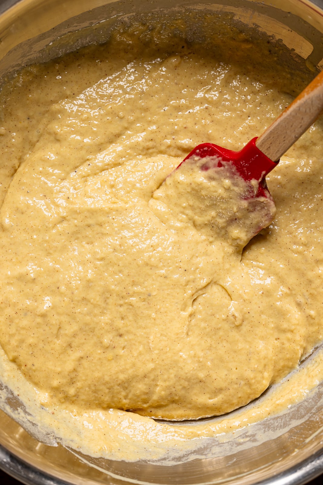 Up close shot of batter in a bowl with a spatula. 