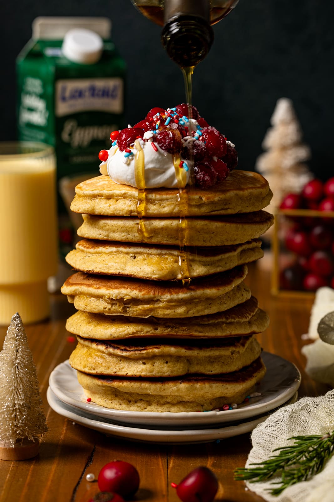 Pancakes with syrup and eggnog in background.