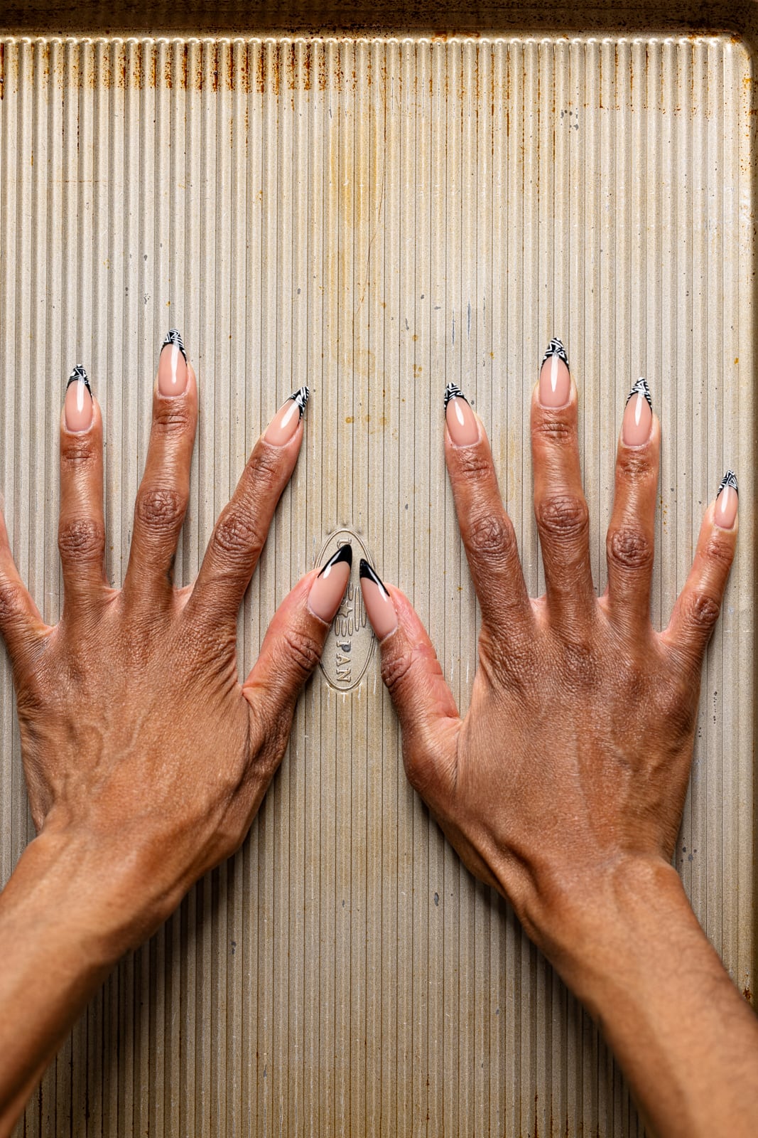 Hands pressing a baking sheet atop tacos.