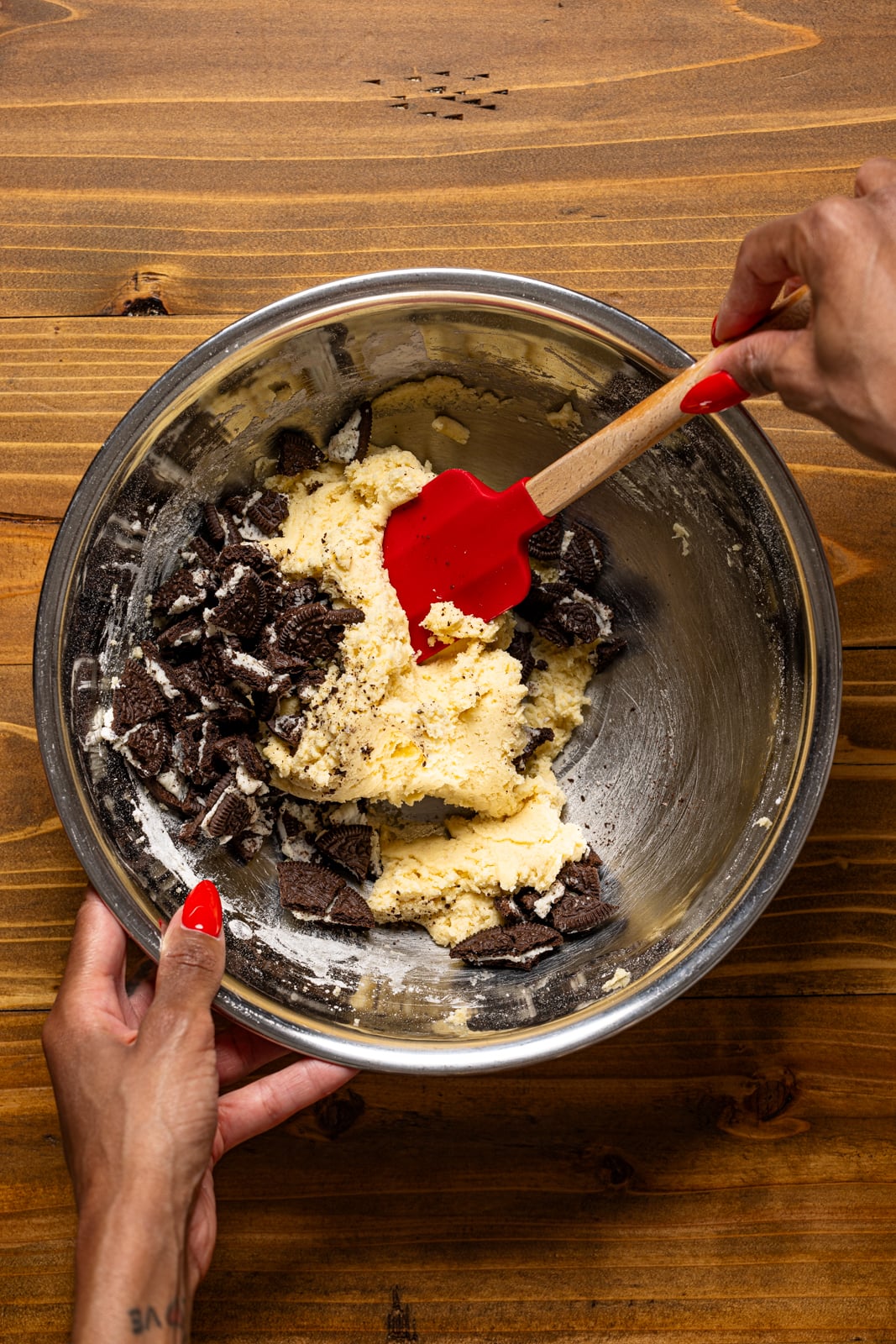 Bowl with cookie batter being held and stirred with spatula. 