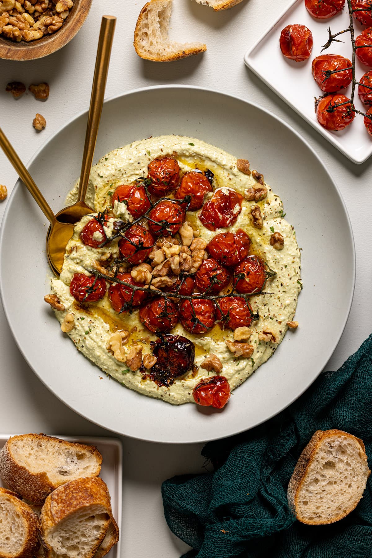 Feta dip in a white bowl with a spoon, fork, and side of bread.