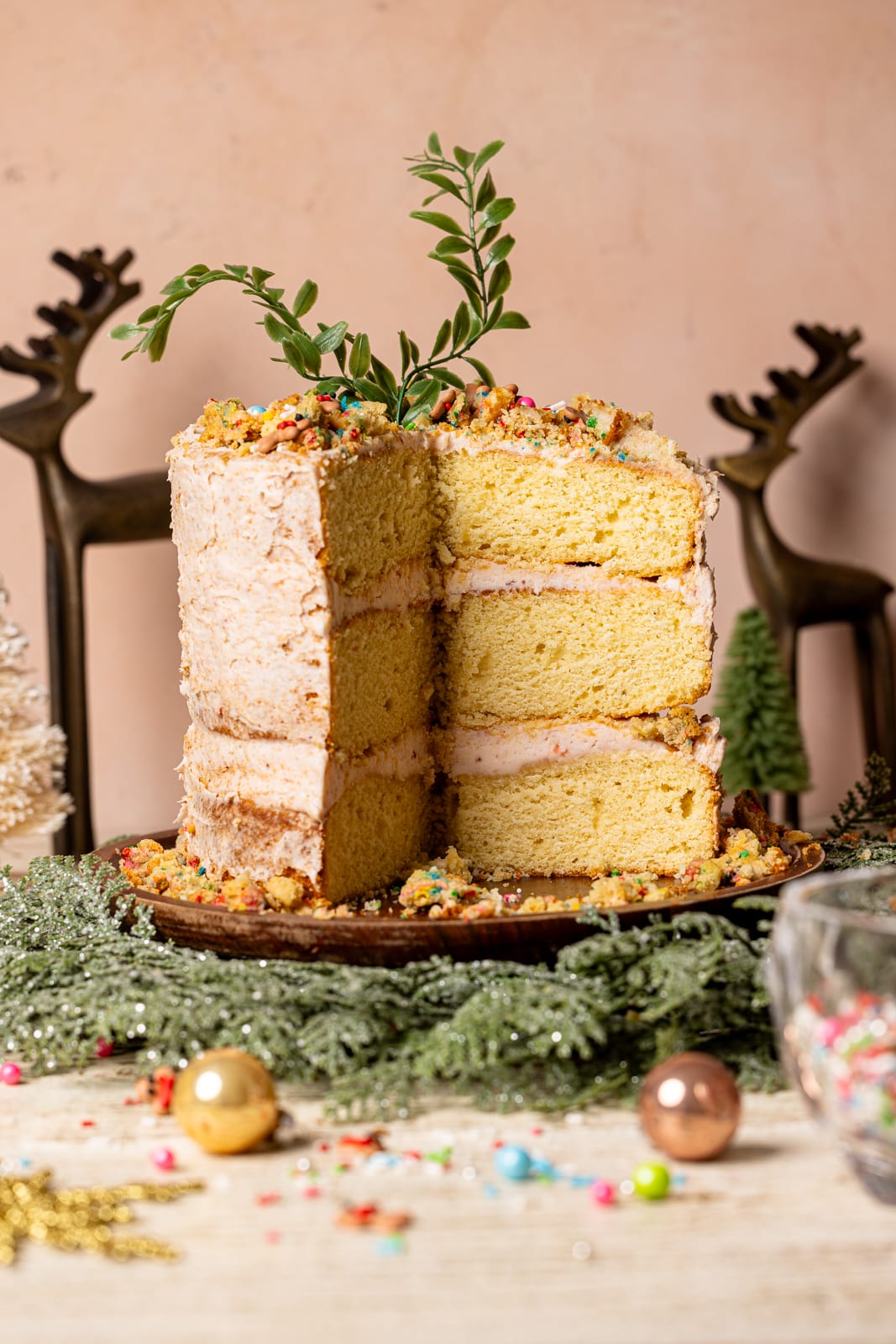 Layered sugar cookie cake on a cake stand with holiday wreath and decor. 