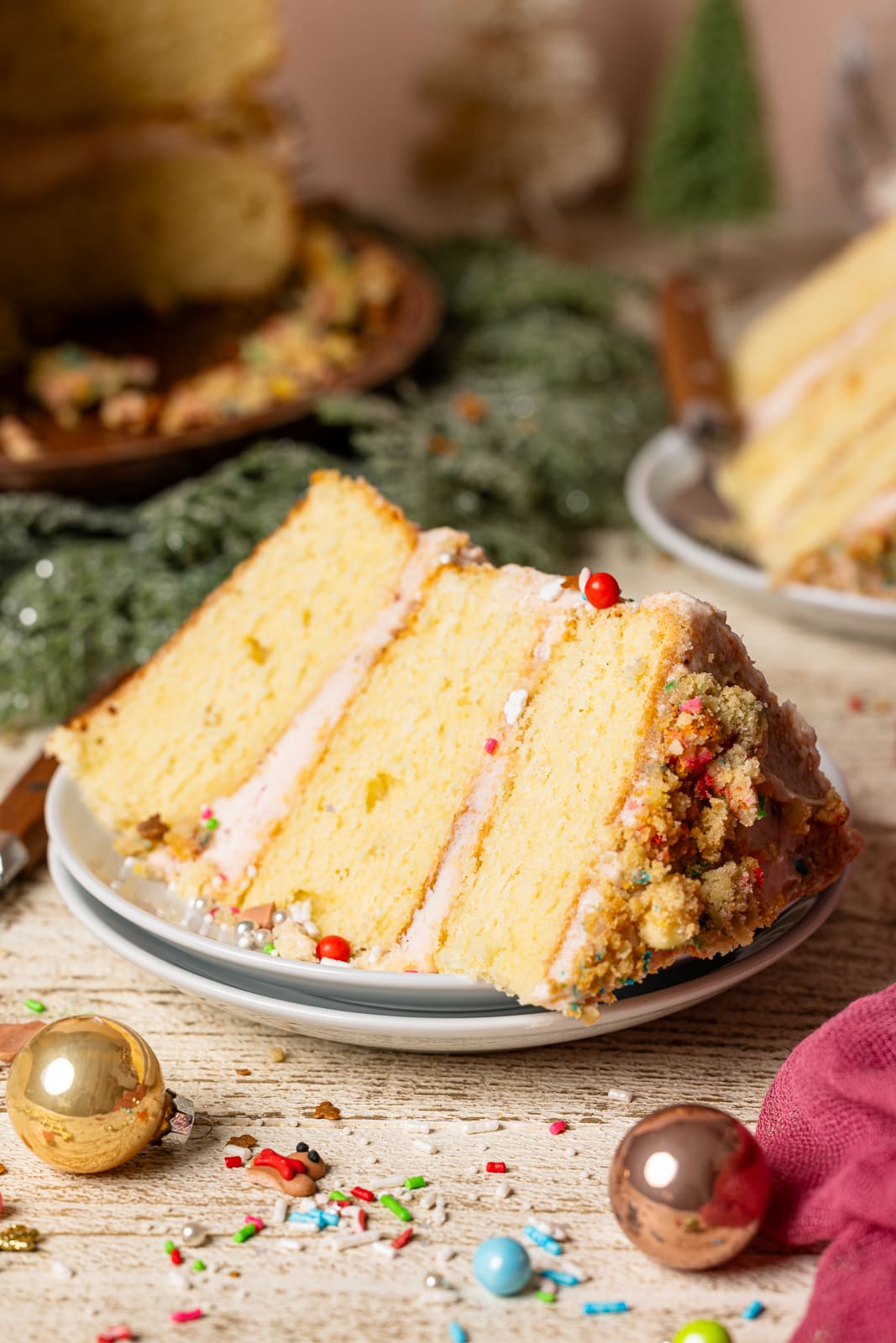 Slice of sugar cookie cake with holiday decor on a white wood table.