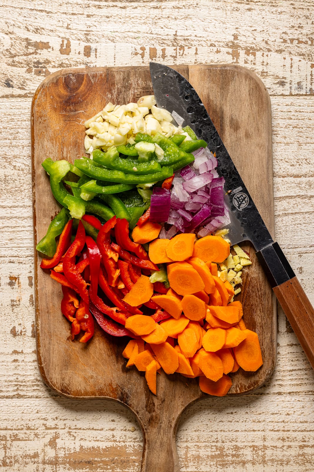 Chopped veggies on a cutting board with a knife.